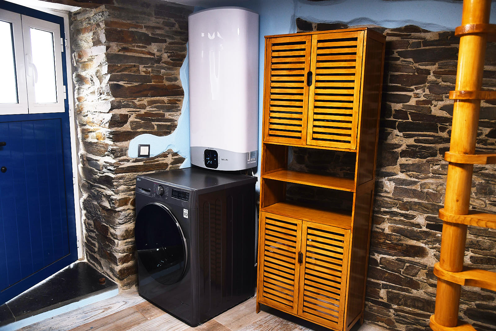Utility area with washing machine, water heater and wooden storage cabinet against an exposed schist wall