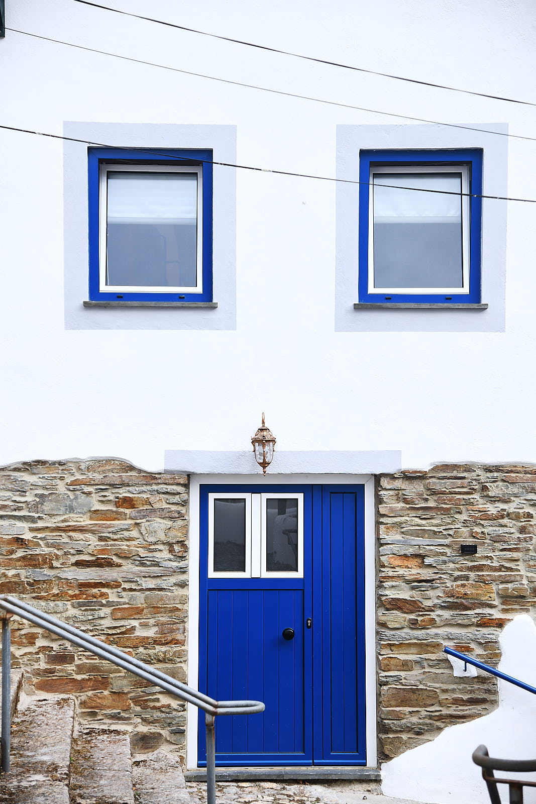 Detail of the traditional blue door with iron hinges and a brass escutcheon