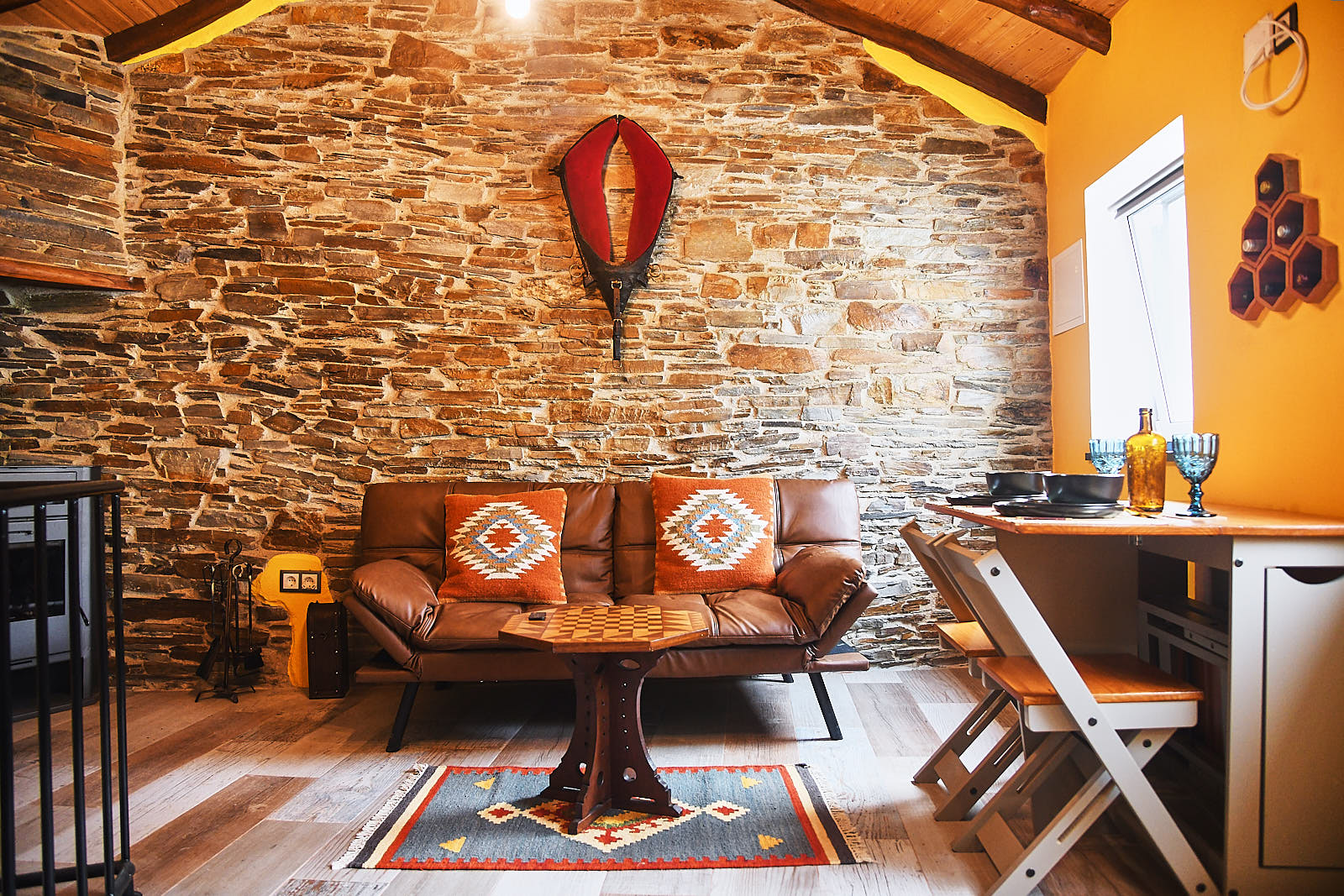 Living room with leather sofa, stone wall and natural light