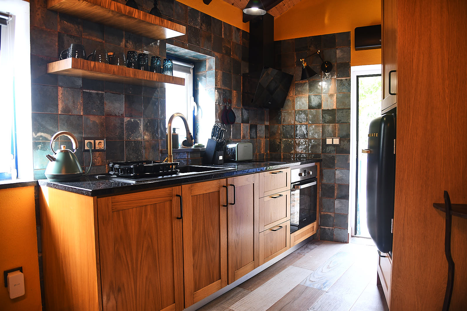 Casa da Égua kitchen with copper-glazed tiles, wooden cabinets, brass faucet and sage-green kettle
